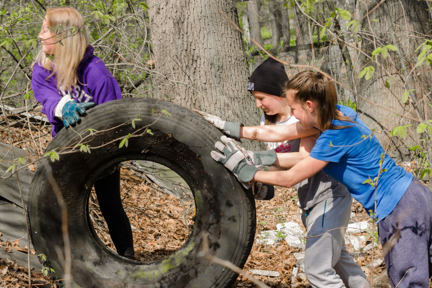 Dívky kutálí pneumatiku mezi stromy
